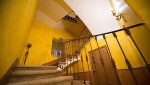 Una escalera con barandilla de madera y pasamanos de metal, que conduce a un rellano con una puerta.