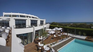 A modern outdoor pool area with multiple seating arrangements and a view of the sea. - Hotel La Plage Art et Emotions (La Grande-Motte)