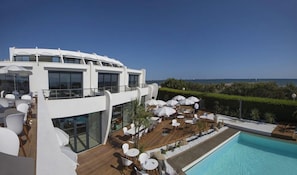 Un área de piscina moderna al aire libre con diversas opciones de descanso y vistas al mar.