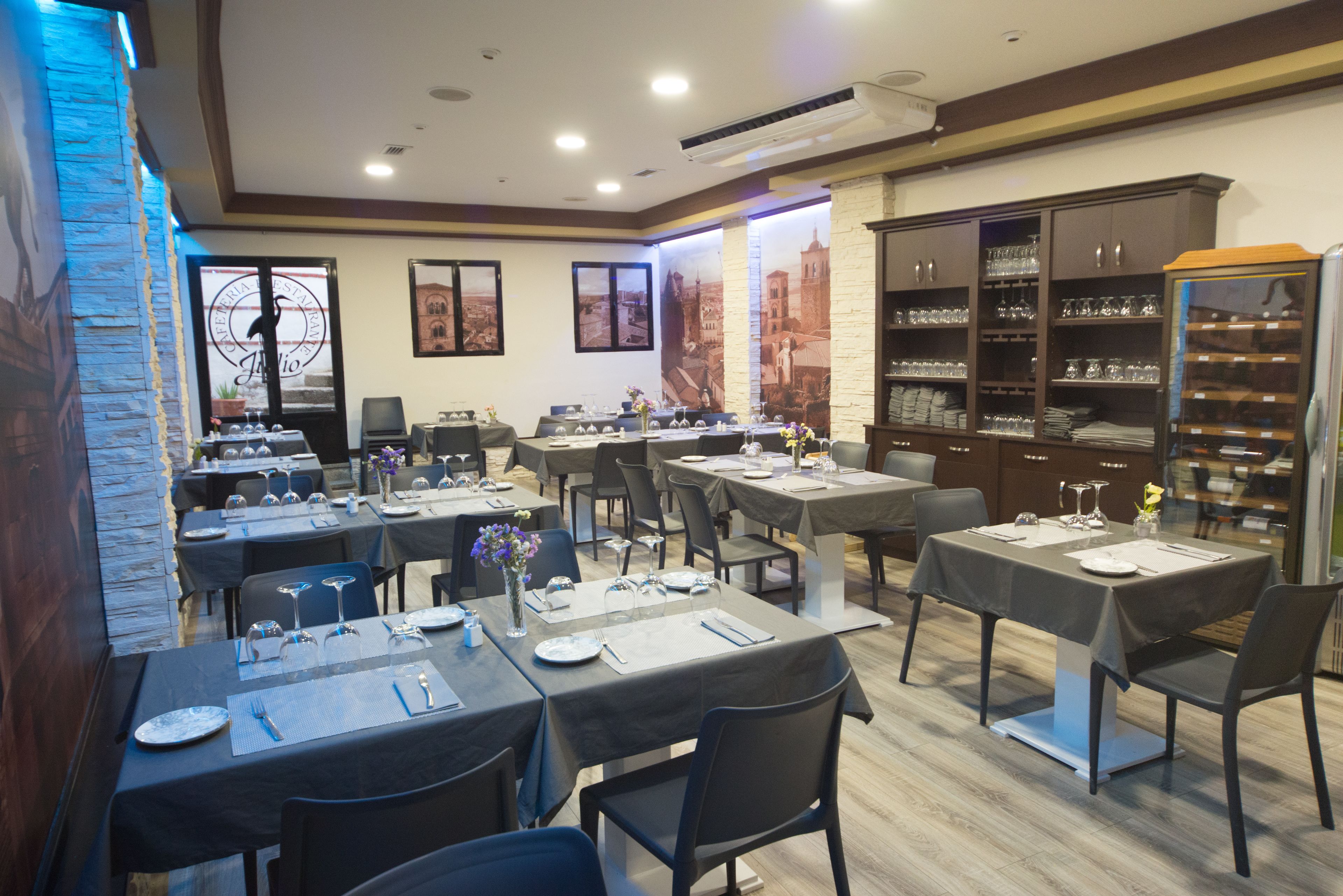 Ein Restaurant mit mehreren gedeckten Tischen, das eine Steinwand und gerahmte Bilder zeigt.