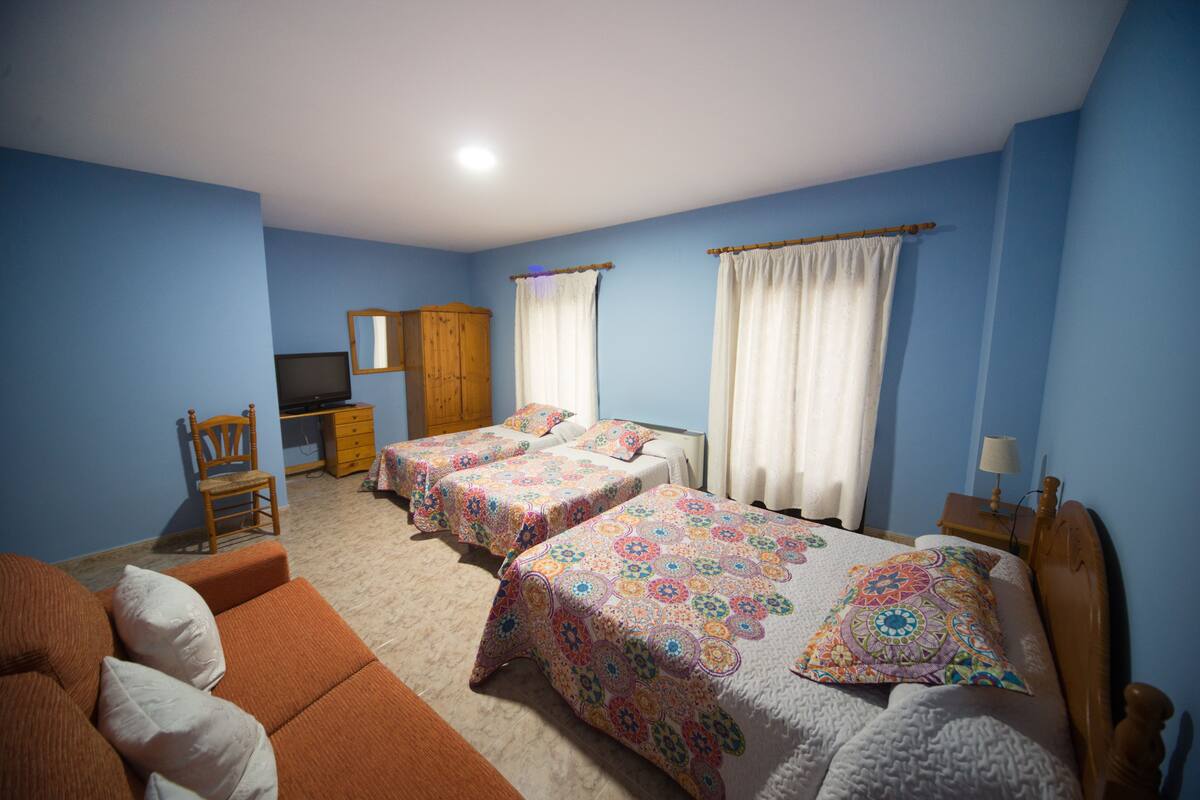A bedroom with two beds, a desk, a chair, and a television.