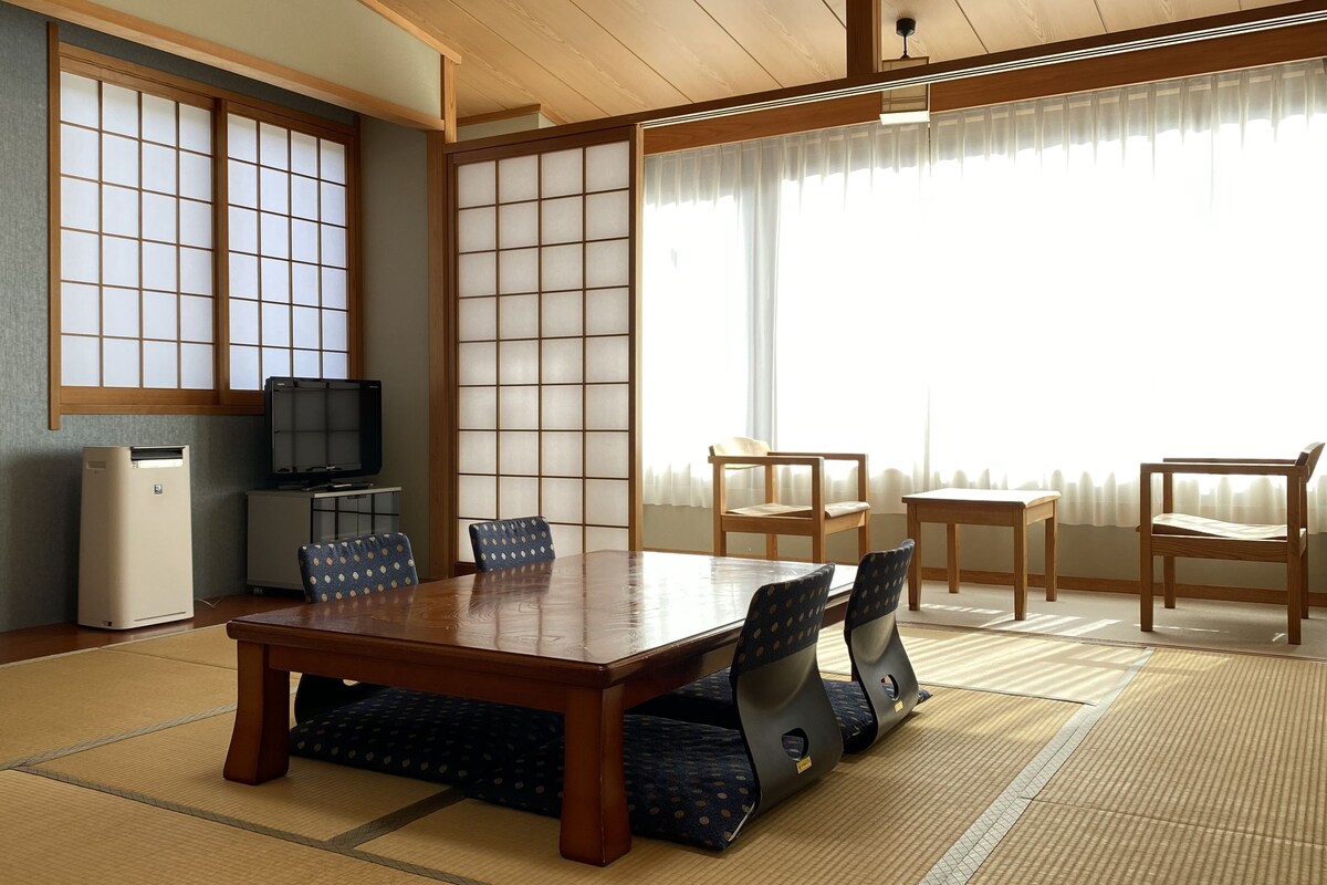 A traditional Japanese-style room with tatami flooring, a low table, and shoji screens.