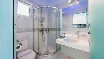 Une salle de bain moderne avec une douche à parois de verre, un lavabo blanc et des toilettes.