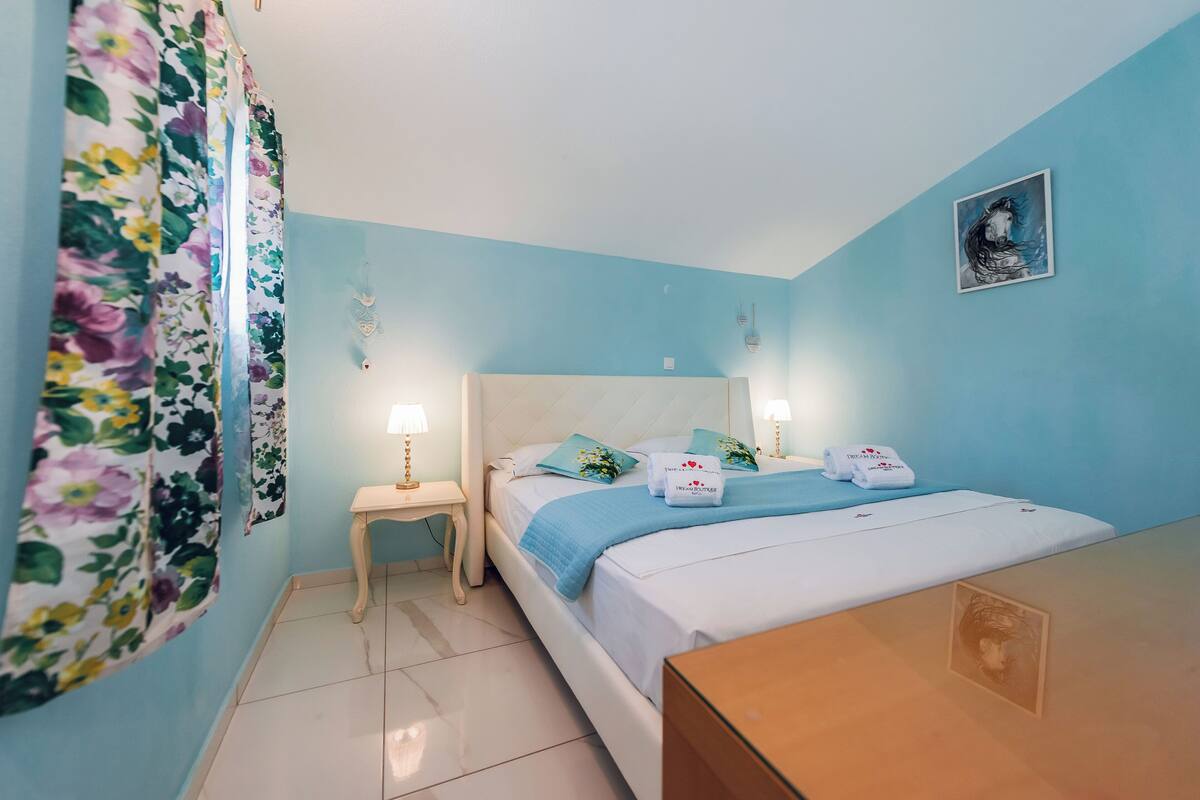A bedroom with a bed, a nightstand, a dresser, and a wall-mounted picture.