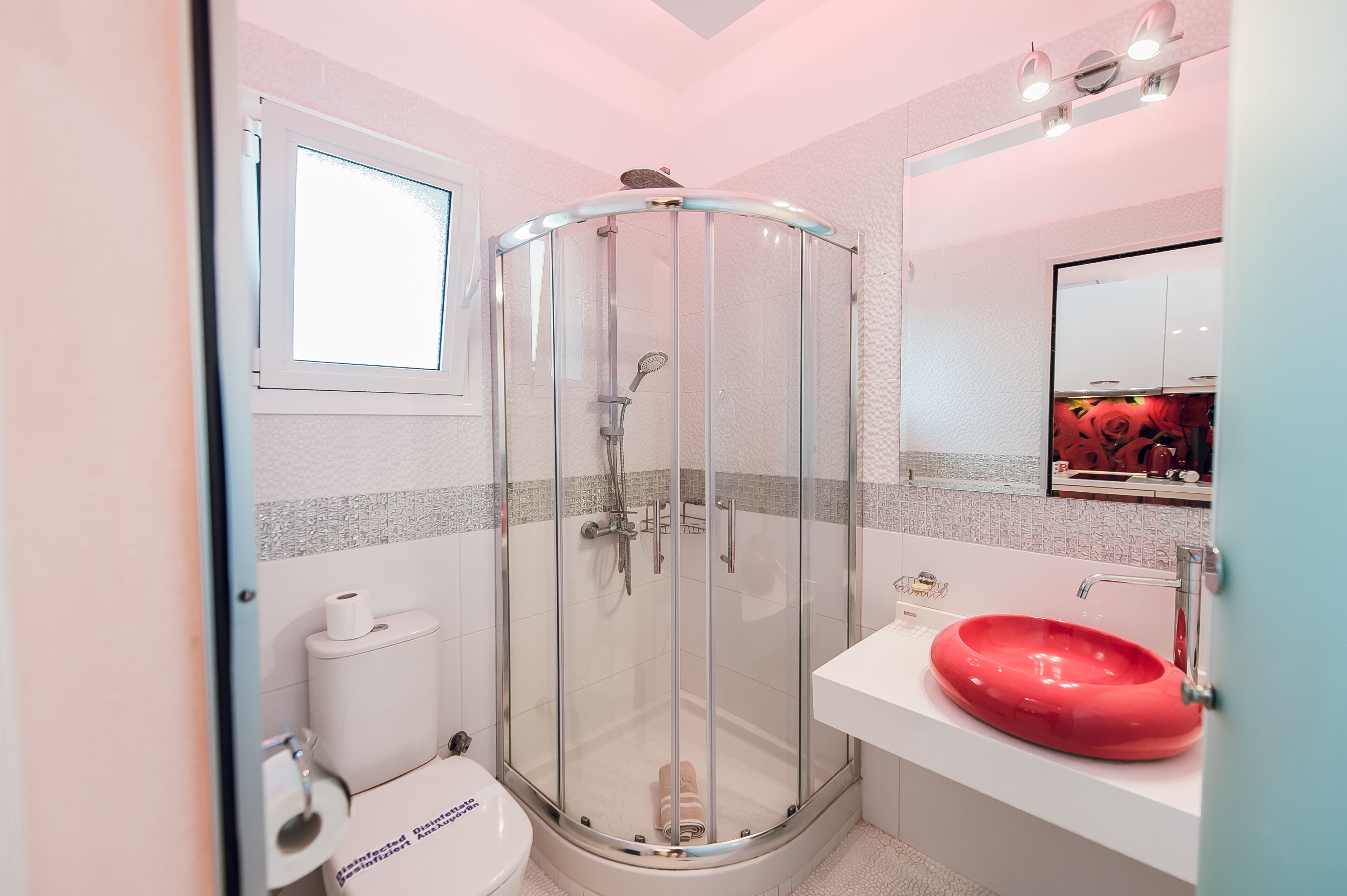 Un baño moderno con cabina de ducha de vidrio, un lavabo blanco y un inodoro.
