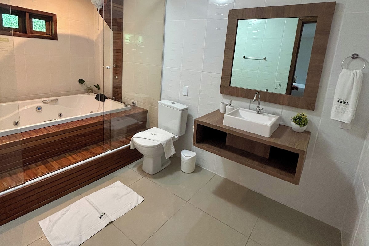 Une salle de bain moderne dotée d’une douche à parois de verre, d’une baignoire sur pieds, de toilettes et d’un meuble-lavabo avec un miroir.