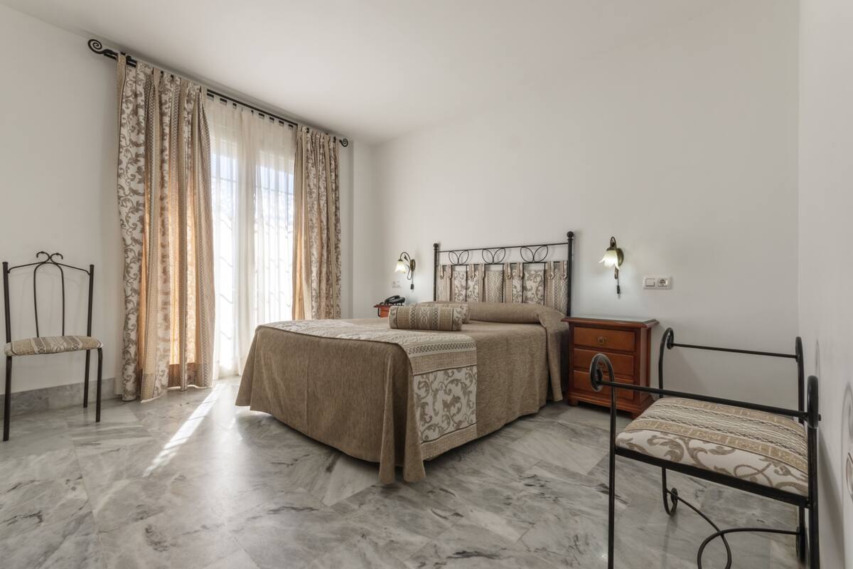 A bedroom with a bed, a nightstand, a chair, and a wardrobe.