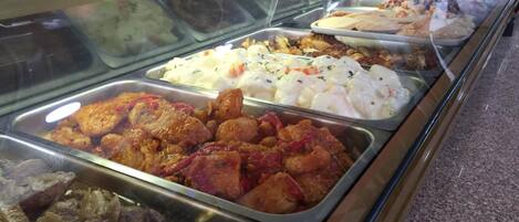 A buffet with various dishes including meats, salads, and other prepared foods.
