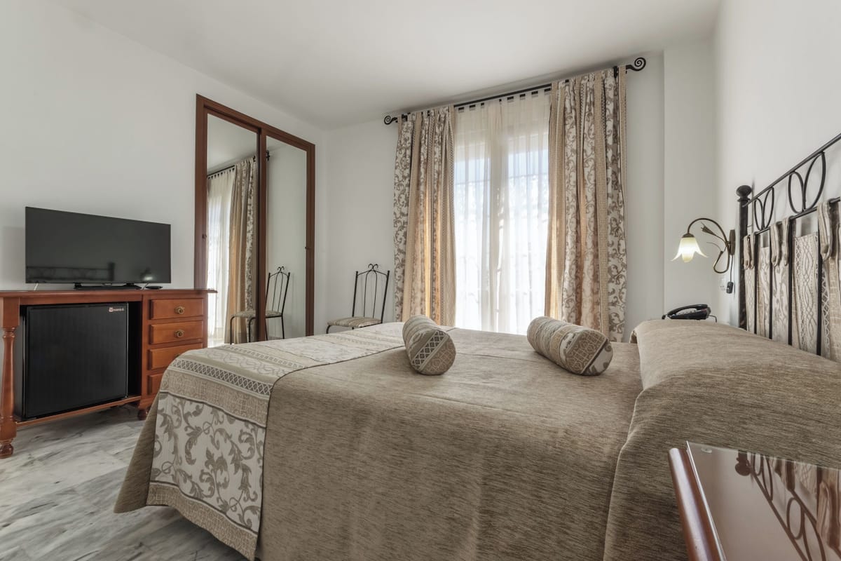 A hotel room with a bed, a desk with a television, and a wardrobe.