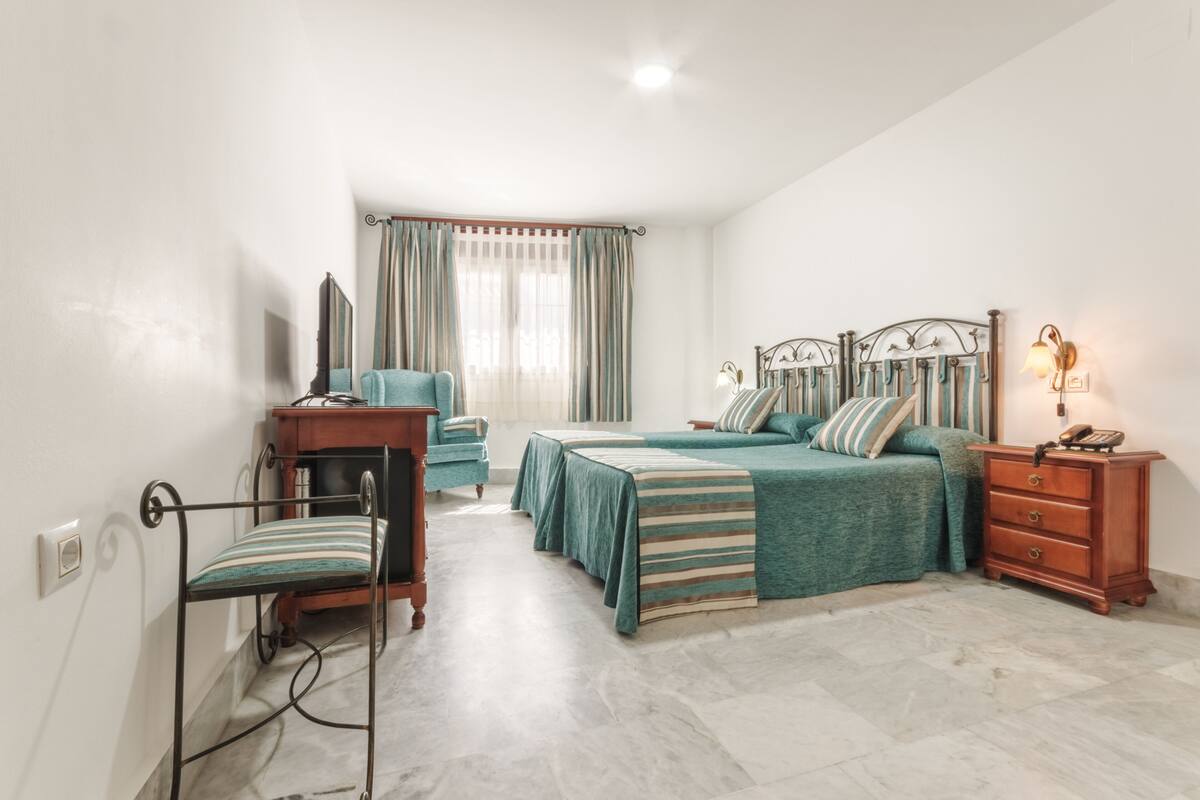 A bedroom with a bed, two bedside tables, a chair, a dresser, and a television.