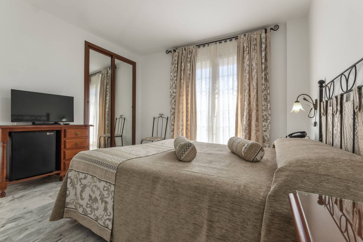 A bedroom with two beds, a desk with a television, and a wardrobe.