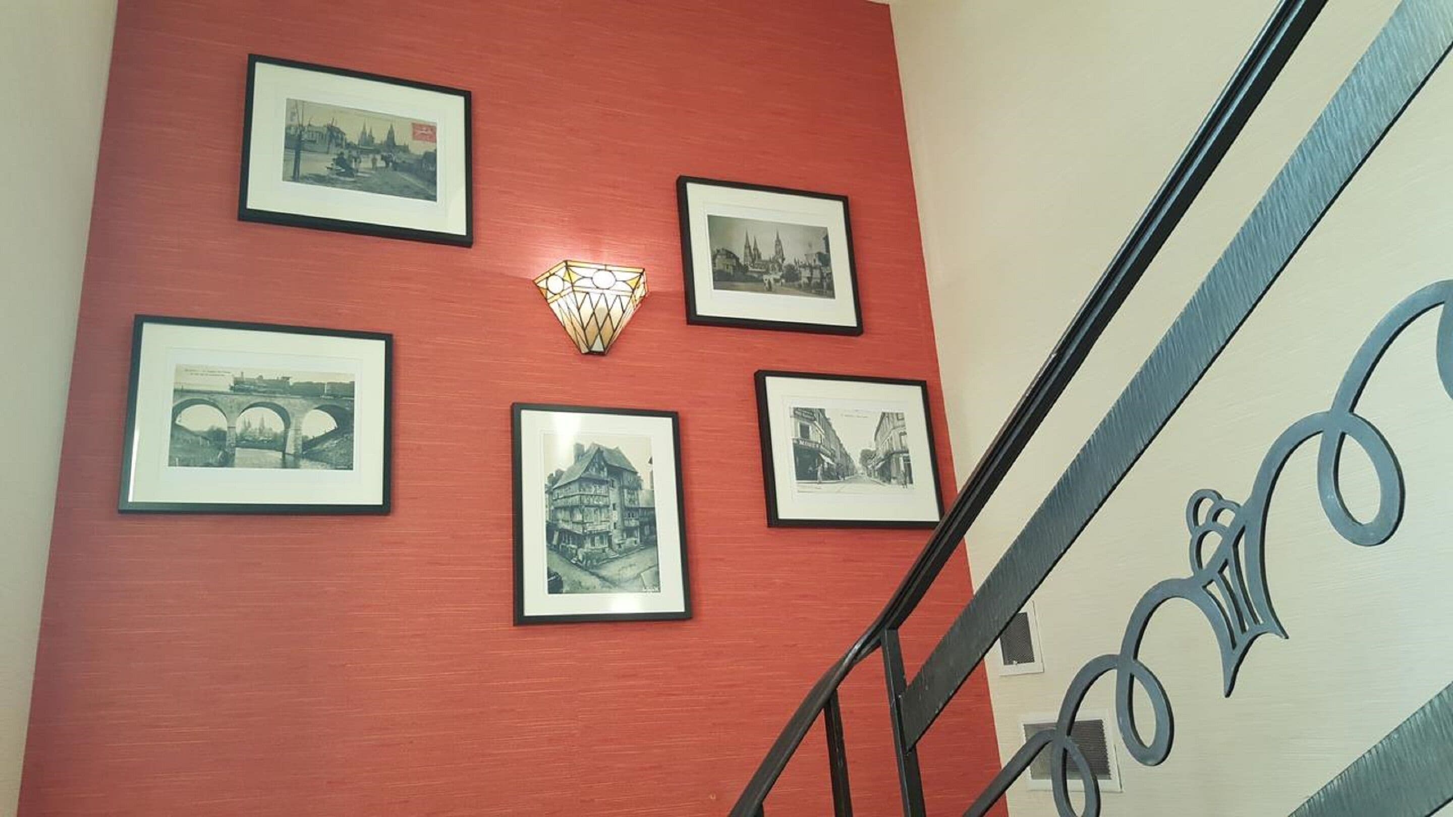 A staircase with a red wall and black-framed photographs.