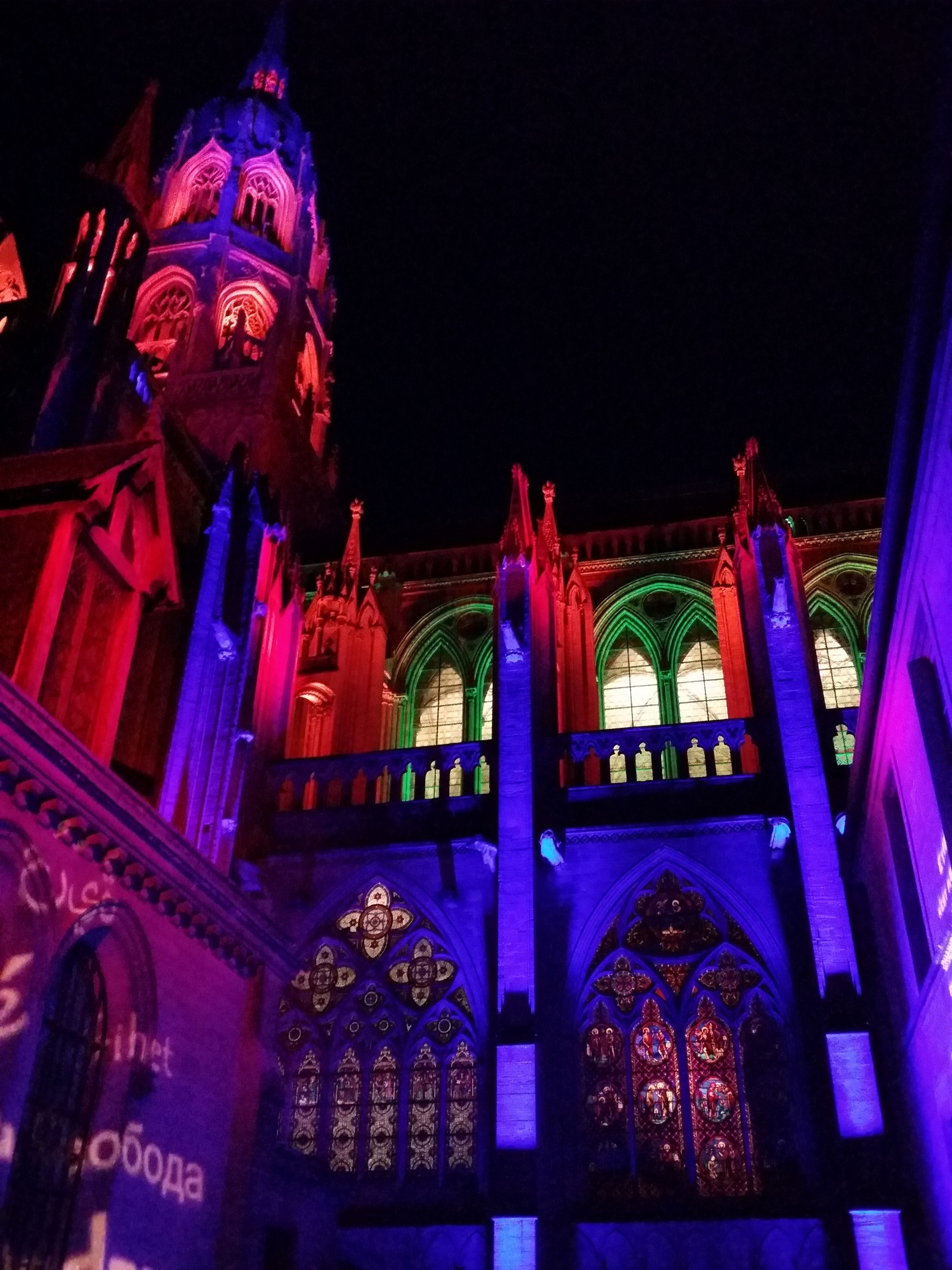 A Gothic-style building with illuminated stained glass windows and a prominent clock tower.