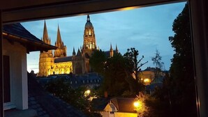 Vista de un edificio histórico con múltiples torres y una destacada torre del reloj, vista desde una ventana al anochecer.