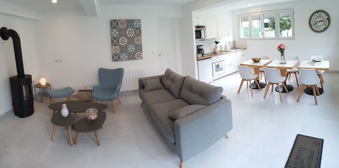 A modern living room with a grey sofa, blue armchairs, and a black wood-burning stove.