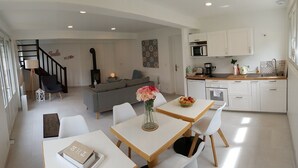 Un espacio de estar moderno con comedor, cocina y una escalera que sube a un nivel superior.