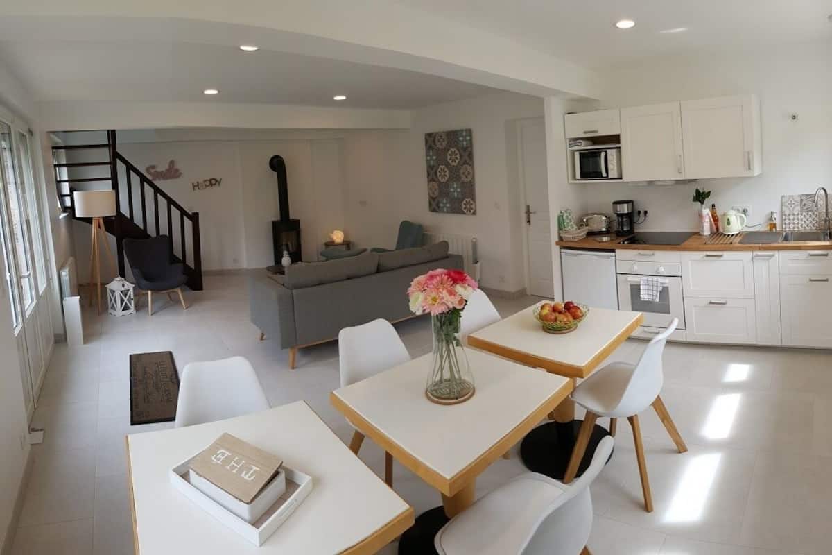 A modern living space with a dining area, kitchen, and a staircase leading to an upper level.