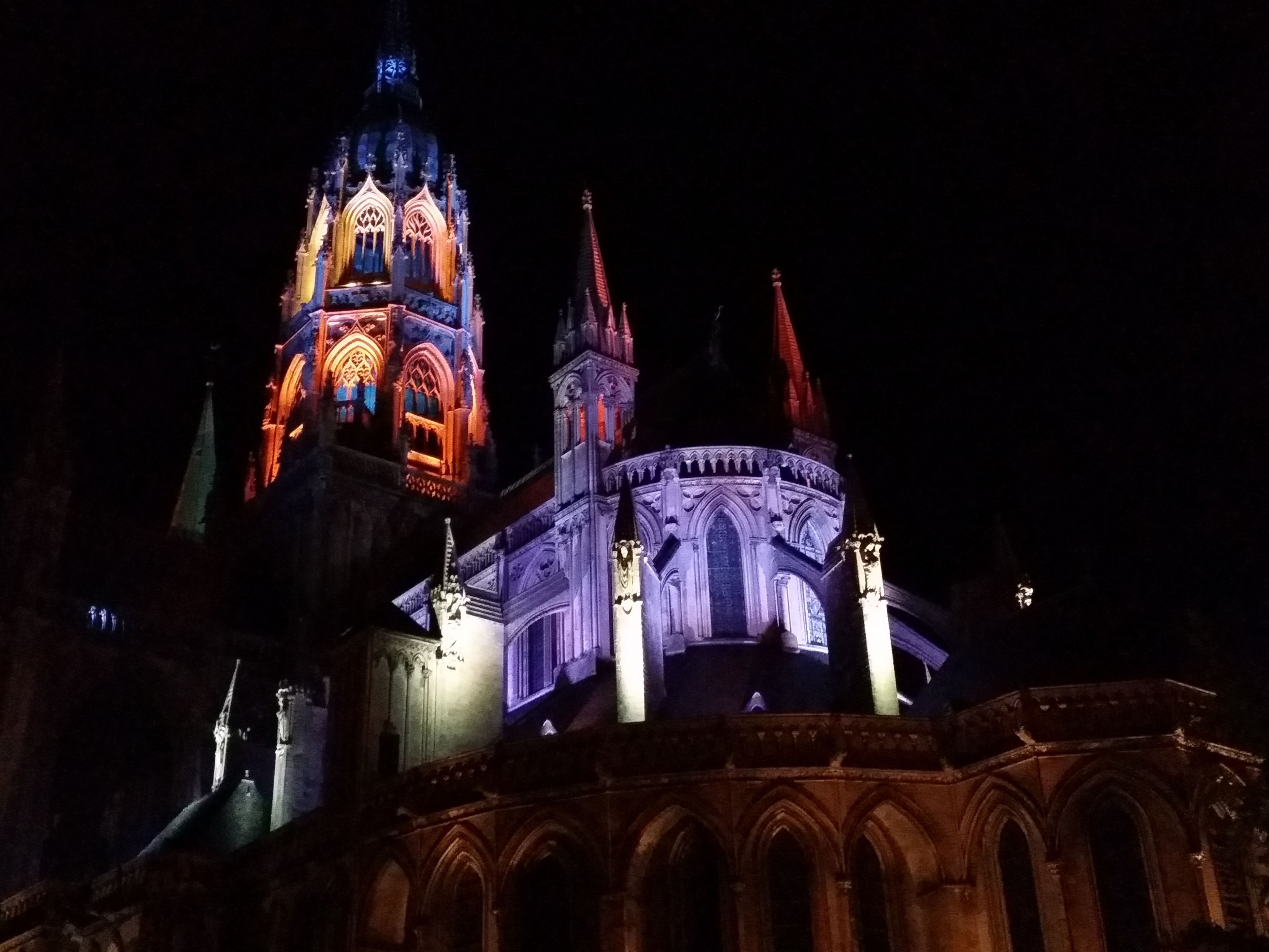 A Gothic-style building with illuminated spires and arches at night.