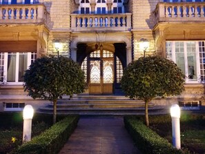 A grand building with a symmetrical facade, a central entrance with a decorative door, and two well-maintained trees flanking the entrance. - Castel Bayeux Guesthouse (Bayeux)