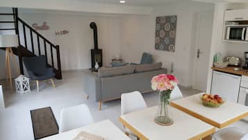A modern living room with a grey sofa, a blue armchair, and a dining area with a table and chairs.