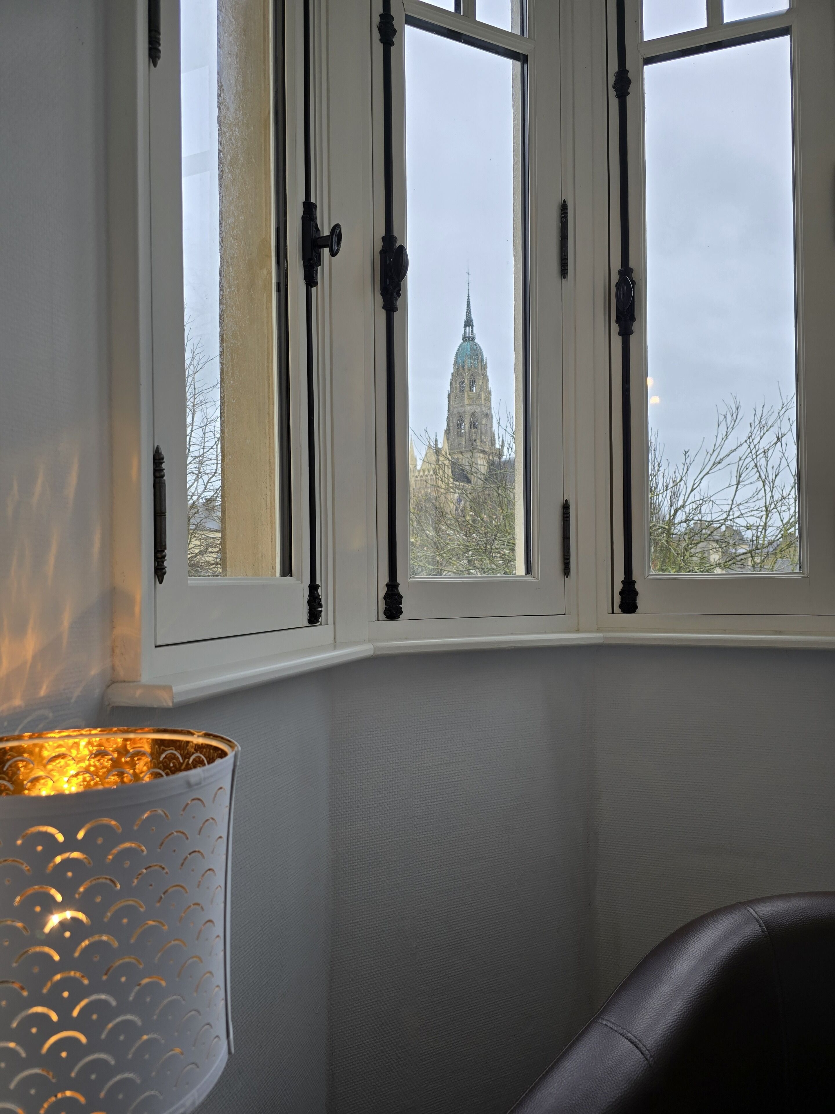 A room with a view of a cathedral through a window with black frames.