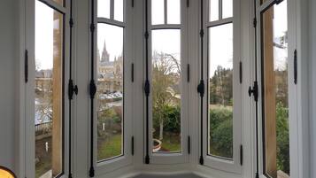 A bay window with multiple panes, offering a view of a historic building and a garden.