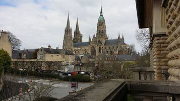 A historic cathedral with twin spires and a green dome, viewed from a bridge with stone railings.