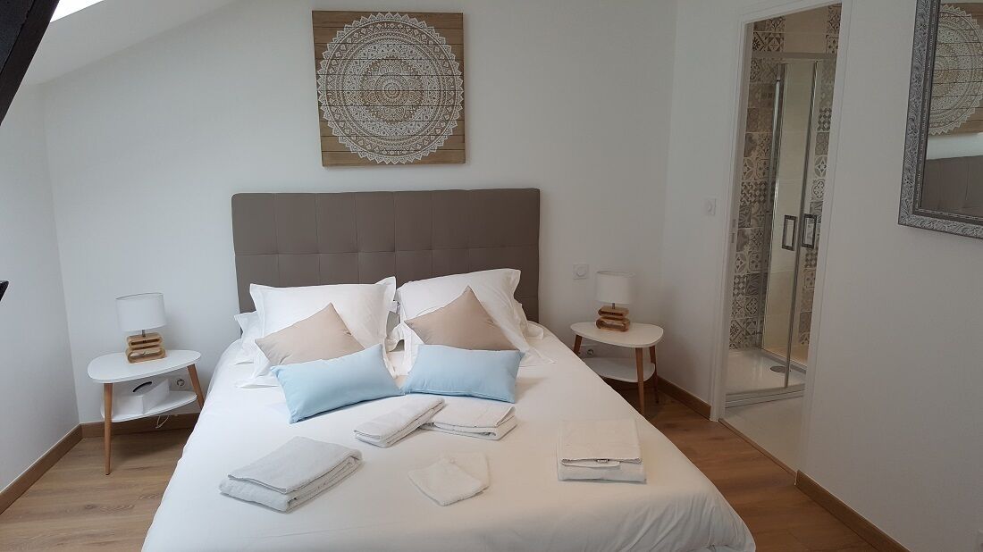 Habitación de hotel con una cama grande, dos mesitas de noche, una obra de arte en la pared y una zona de ducha.