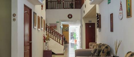 A hotel lobby with a staircase, a reception desk, and two sofas.
