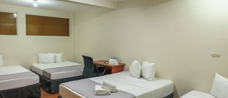Habitación de hotel con tres camas, un escritorio y una silla.