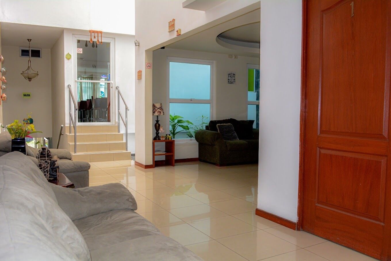 A spacious living area with a sofa, a coffee table, and a plant. There is a staircase leading to another room.