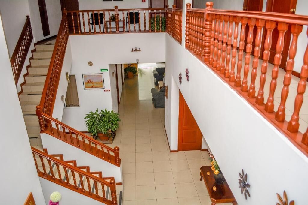 A multi-level interior with wooden staircases and railings, a hallway leading to a room, and a potted plant.