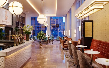 A hotel lobby with a bar area, seating, and a large window offering a view of the outside.