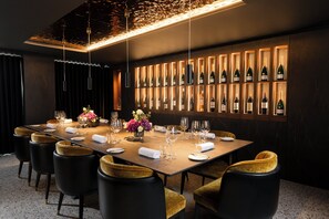 A dining area with a long table, multiple chairs, and a wall of wine bottles. - Grand Central Hotel Belfast (Belfast)