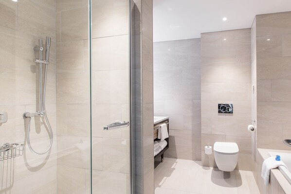 Ein modernes Badezimmer mit Duschkabine aus Glas, Toilette und Badewanne.