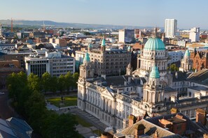 A historic building with a large dome and multiple spires, surrounded by modern buildings and a clear sky. - Grand Central Hotel Belfast (Belfast)
