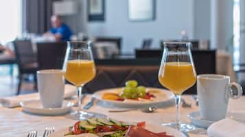 A breakfast table with plates of food, glasses of orange juice, and cutlery.