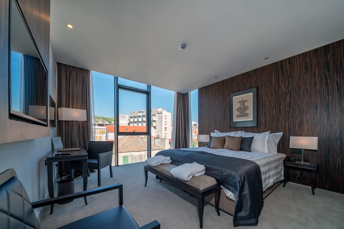 Une chambre d’hôtel moderne avec un grand lit, un bureau, une chaise et une vue sur la ville.