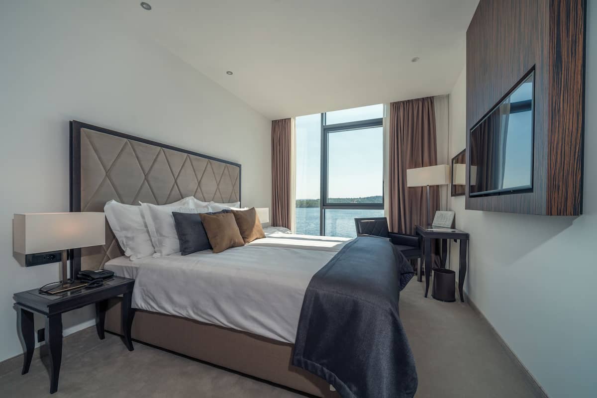 Une chambre d’hôtel moderne dotée d’un grand lit, d’un bureau, d’une chaise, d’une télévision et offrant une vue sur l’eau.