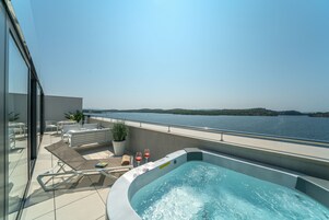 A rooftop terrace with a hot tub, seating area, and a view of the water.