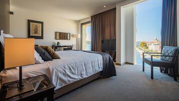 Une chambre d’hôtel avec un grand lit, un bureau, une chaise, une télévision et un balcon offrant une vue sur la ville.