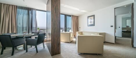 Ein modernes Hotelzimmer mit Essbereich, einer Couch und einem großen Fenster.