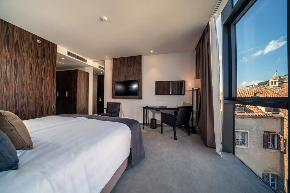 Une chambre d’hôtel avec un grand lit, un bureau, une télévision et une vue sur la ville.