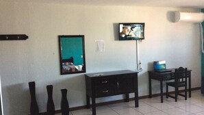 Ein Hotelzimmer mit einem Bett, einem an der Wand befestigten Fernseher, einem Schreibtisch mit Stuhl und zwei Vasen auf dem Boden.