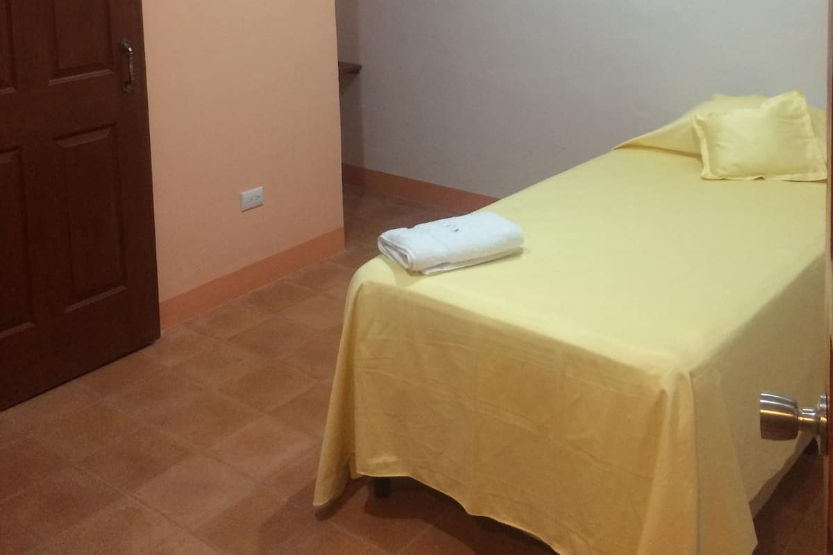 A room with a bed, a ceiling fan, and a door.