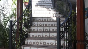 Una escalera con barandillas de metal ornamentadas y azulejos estampados.