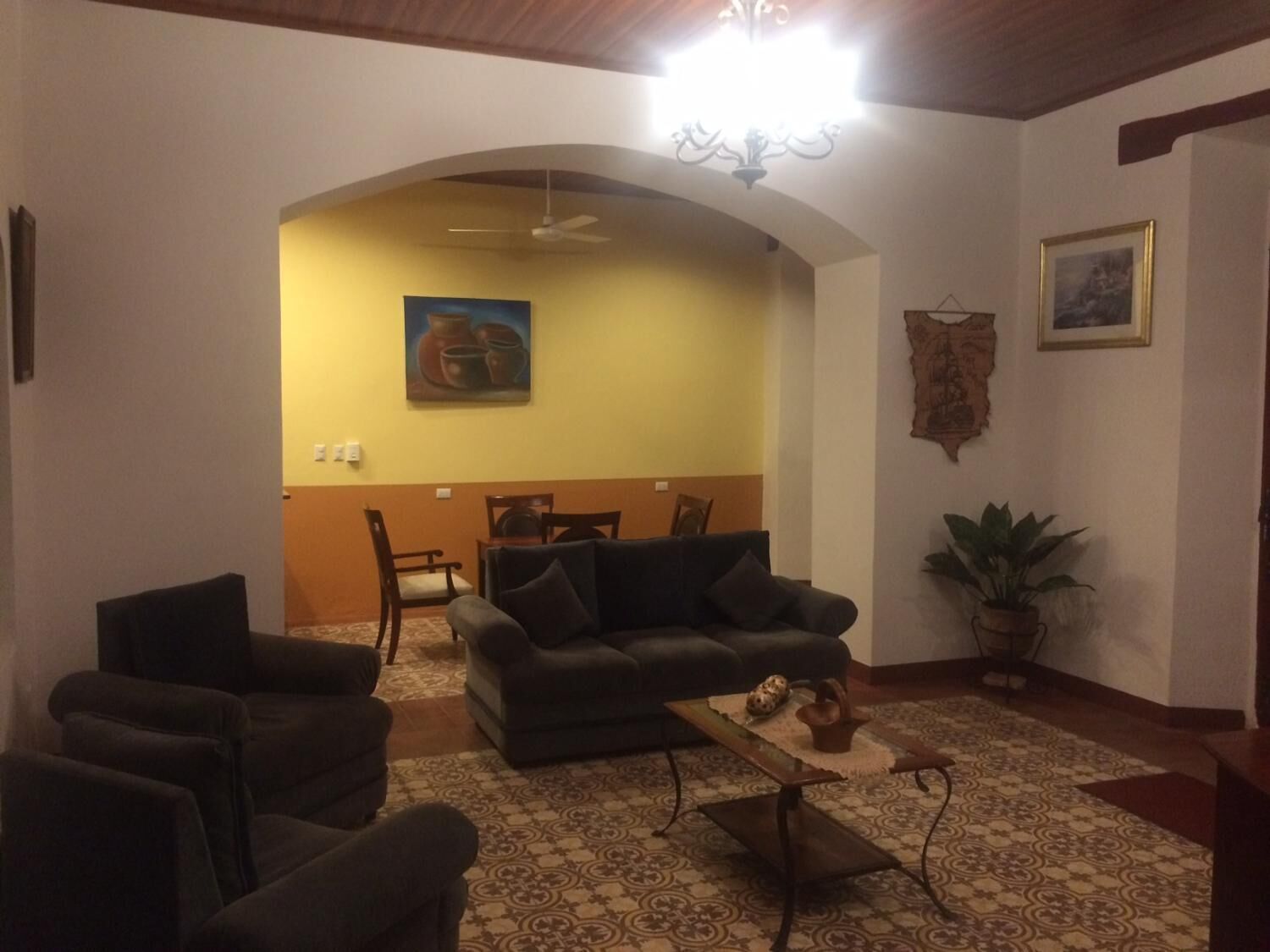 A living room with a dark sofa, armchairs, a coffee table, and a dining area with chairs and a table.