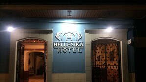 Exterior del hotel Hellenika, con un letrero sobre la entrada y dos puertas.
