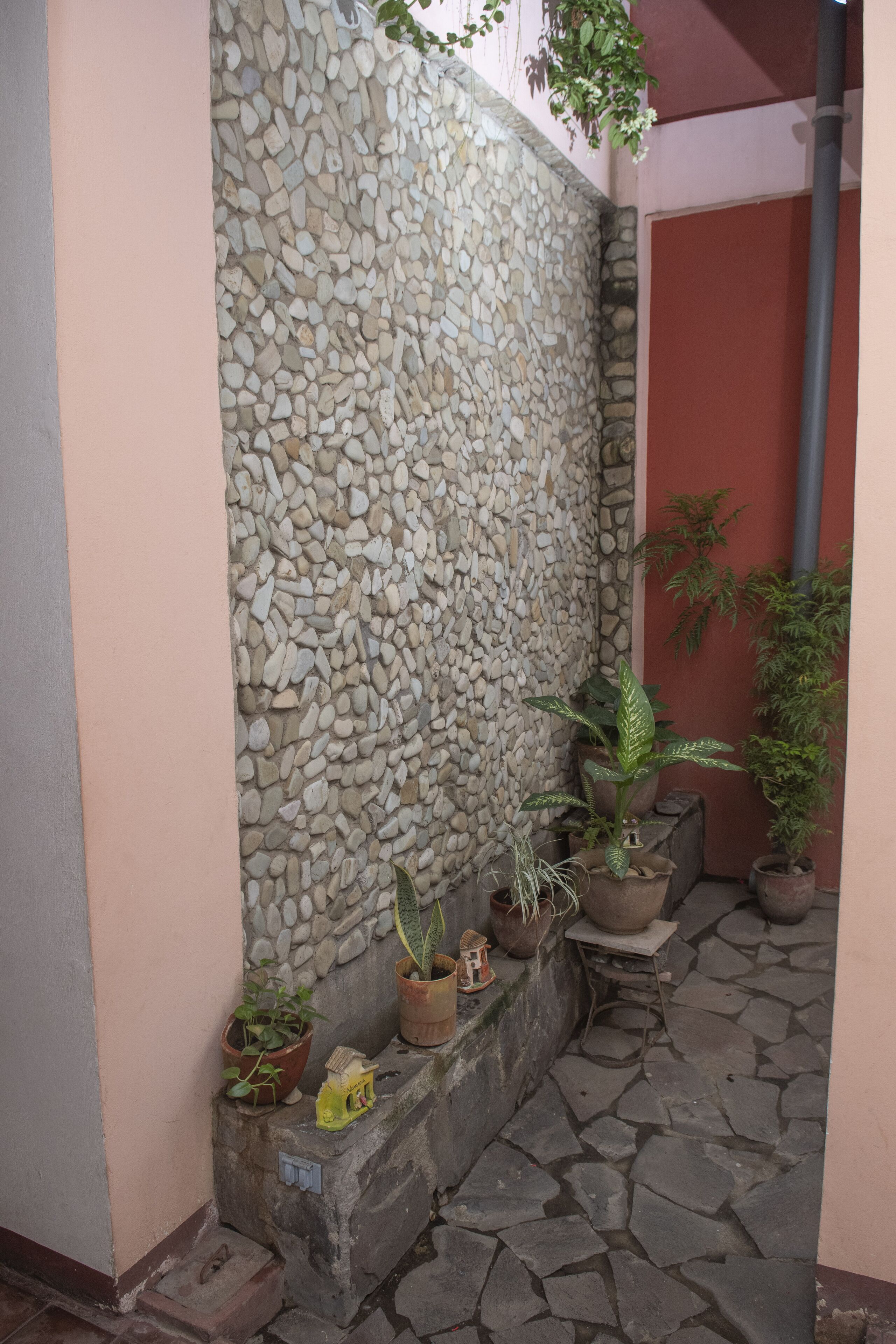 A stone wall with potted plants, a small table, and a tiled floor.