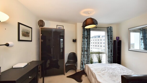 A bedroom with a bed, a desk, a chair, a wardrobe, and a window with curtains. - Belgravia Apartments- Wilton Road (London)